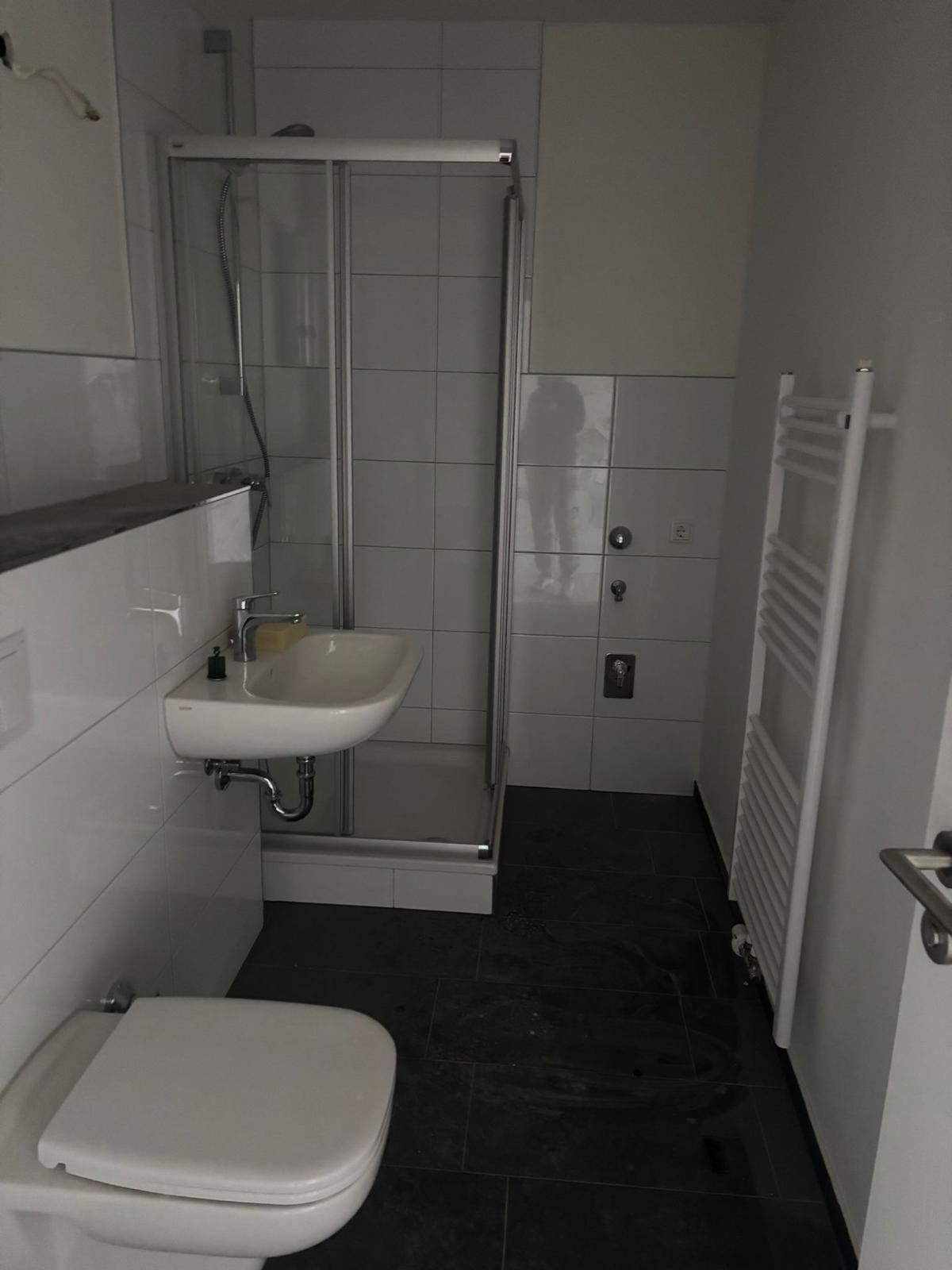 Badsanierung: Dusche, dunkle Bodenfliesen, Handtuchheizkörper